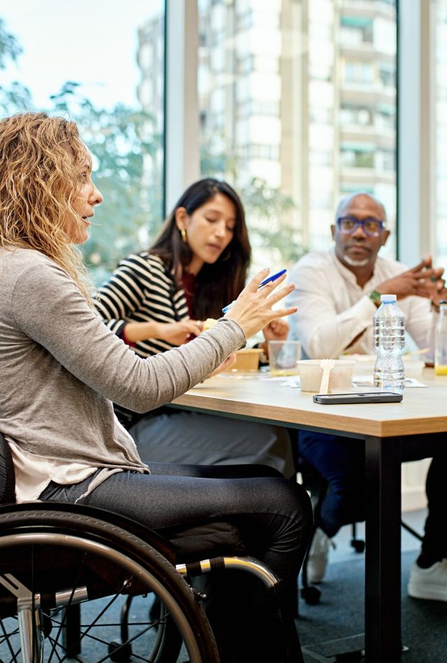 Group of corporate professionals sitting around conference table talking