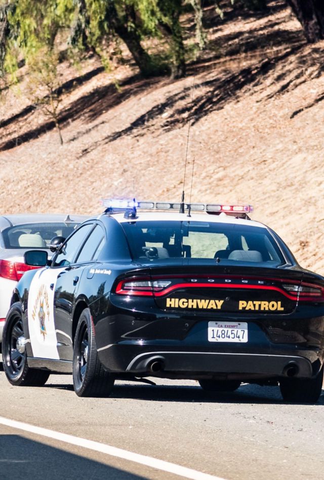 A police officer has pulled over a car and is speaking to the driver on the side of the road