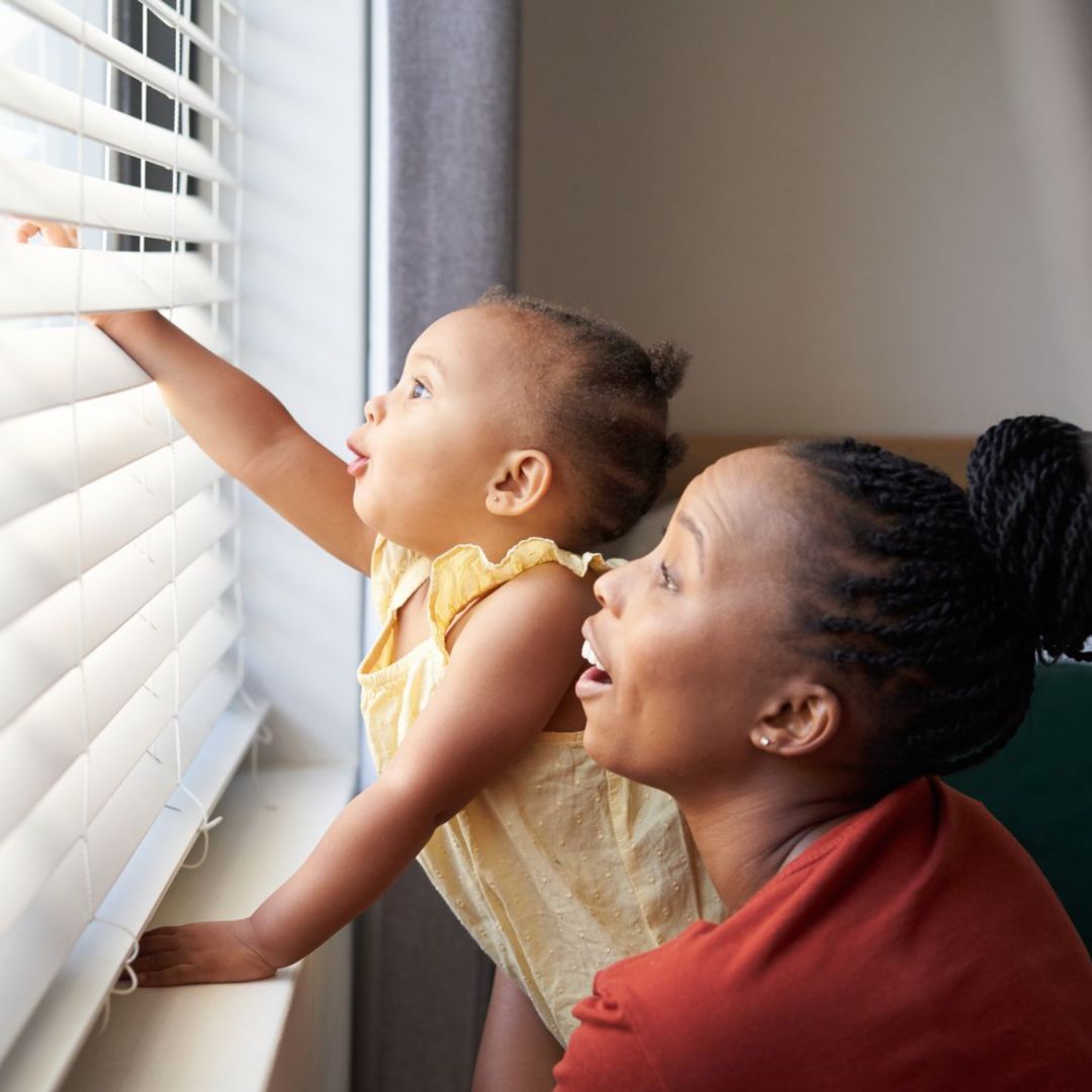 A woman and baby look out a window