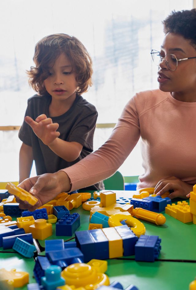 Teacher sitting with studens and using toy blocks