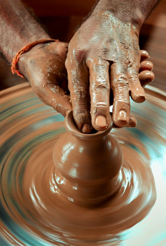 Close up of someone shaping clay on a pottery wheel