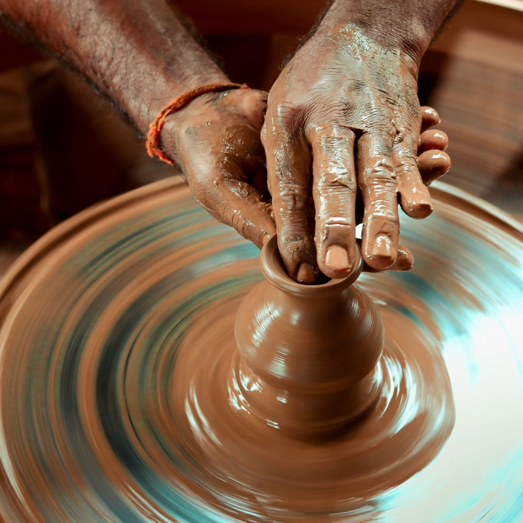 image of hands creating pottery at a pottery wheel