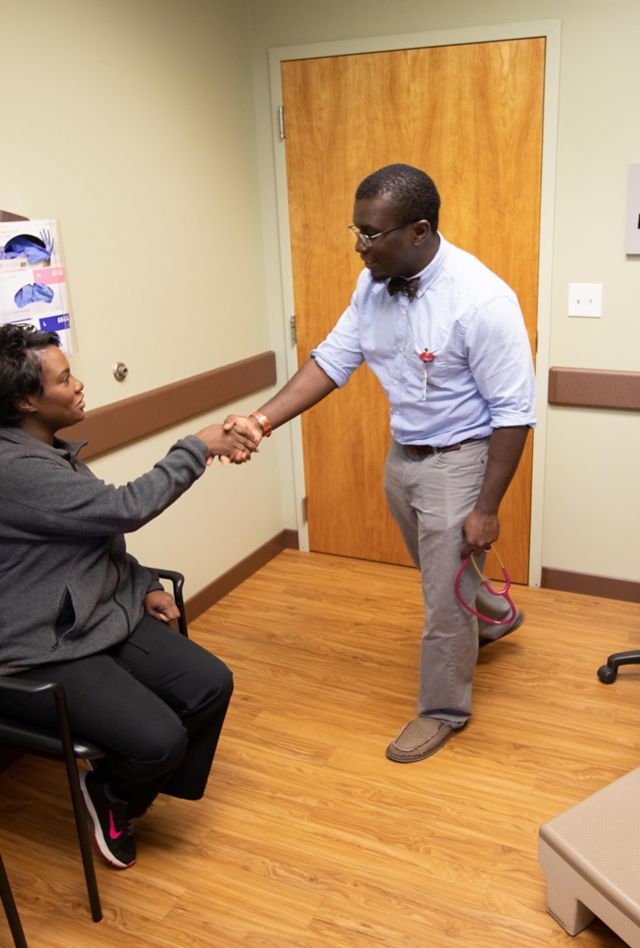 PYGK62 African-American doctor checks patient's heart and lungs with stethoscope during routine medical examination.