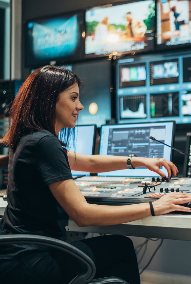 Young woman working in a broadcast control room on a tv station