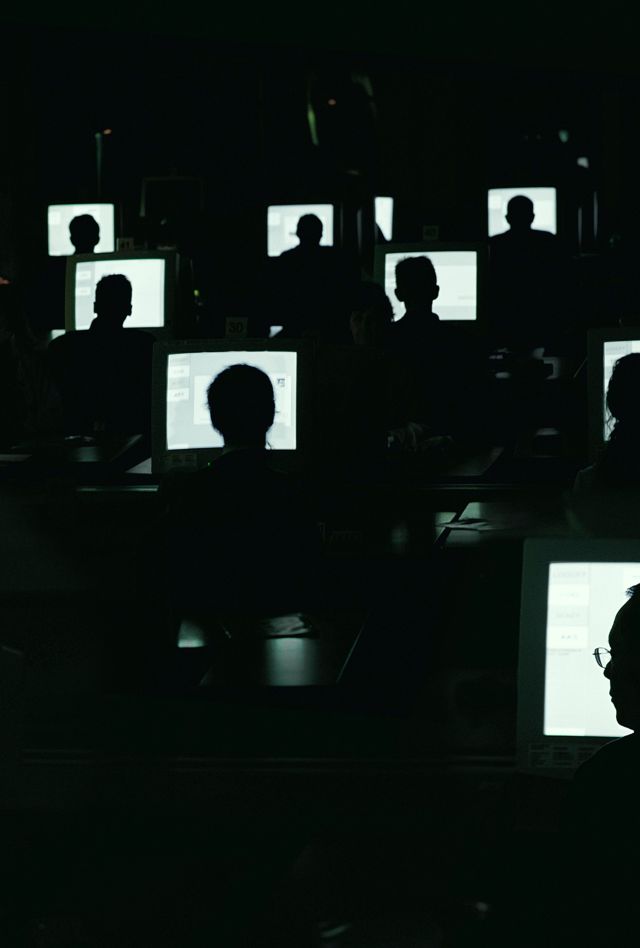 People working in dark room on computers.