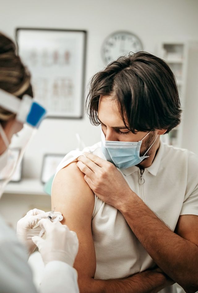 Health provider giving a shot to a young man
