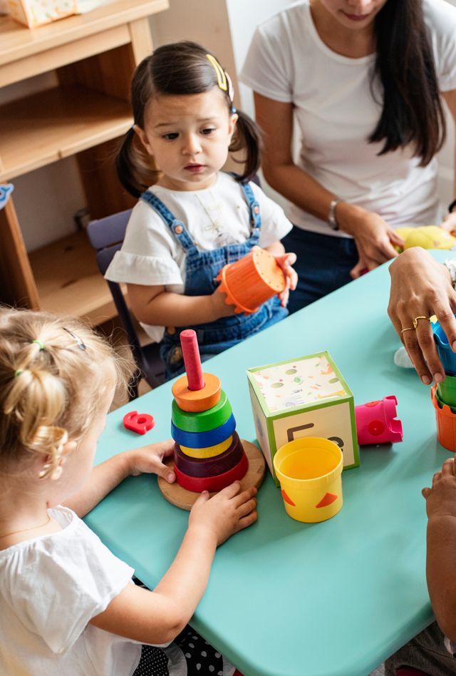 Nursery children playing with teacher in the classroom