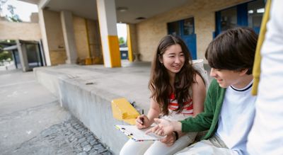 Teens sitting outside building and talking