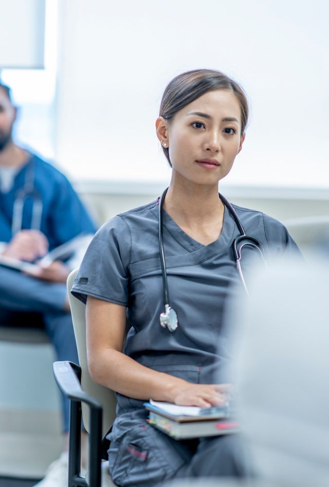 A diverse group of medical students sit in class and listen to their professor.