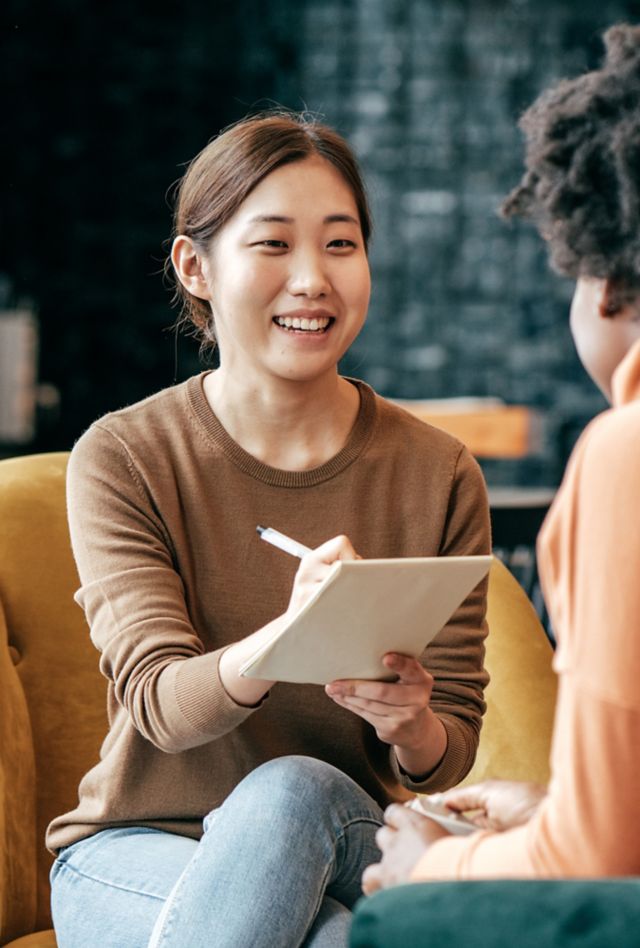 Woman with a note pad interviewing another person