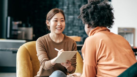 Woman with a note pad interviewing another person