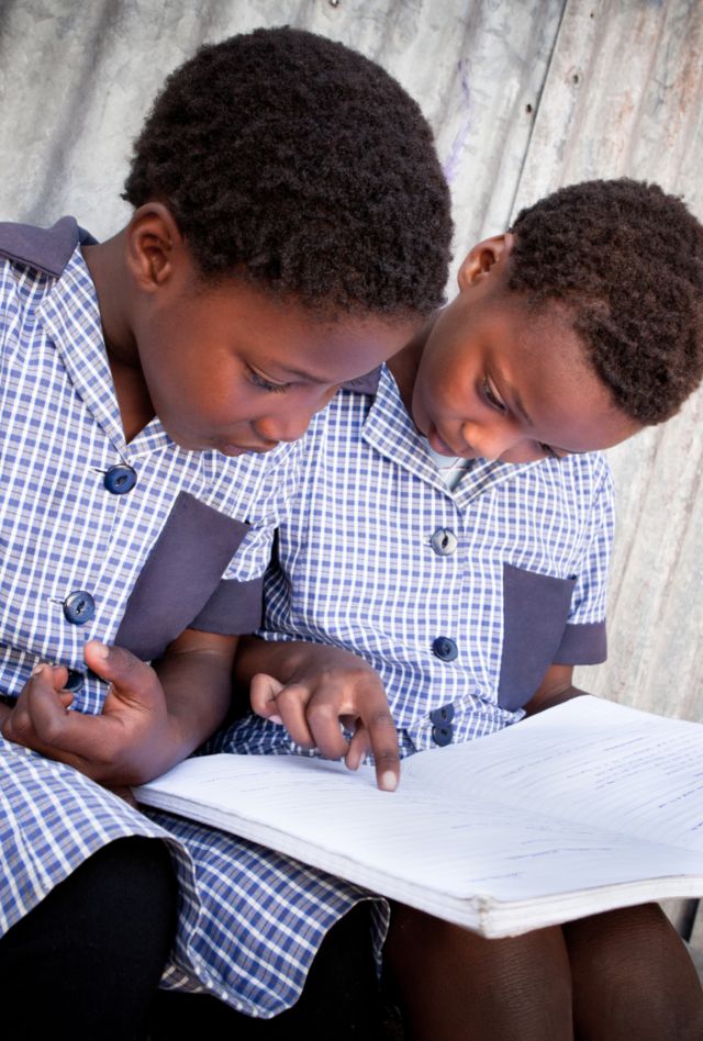 Two young African girls sitting and studying