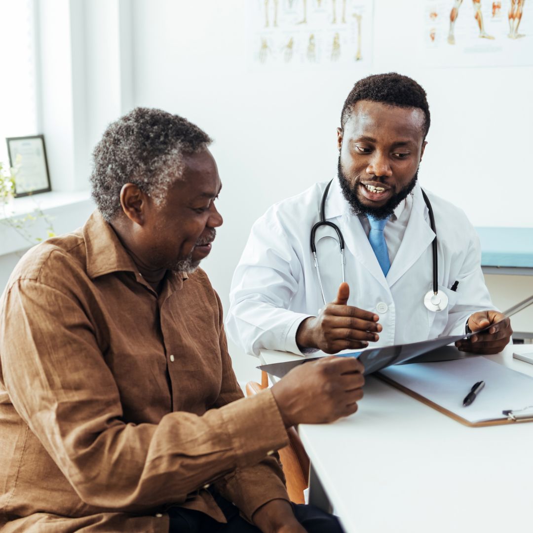 Male doctor and senior patient looking at a file in an office.