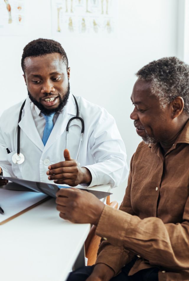 Male doctor and senior patient discussing scan results at the office.