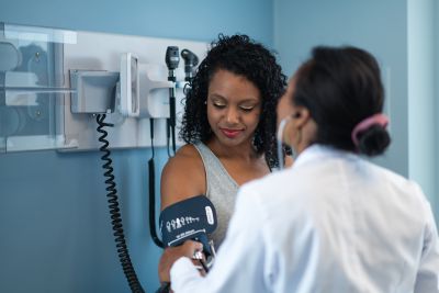 A young woman has her blood pressure checked by her medical provider