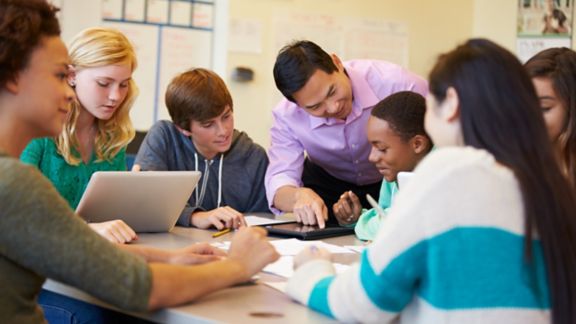 High School Students With Teacher In Class Using Laptops Smiling