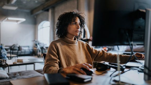 Woman with brown sweater working at a computer in an office