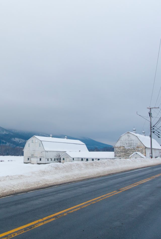 Snowy farmhouse from road with field and hills