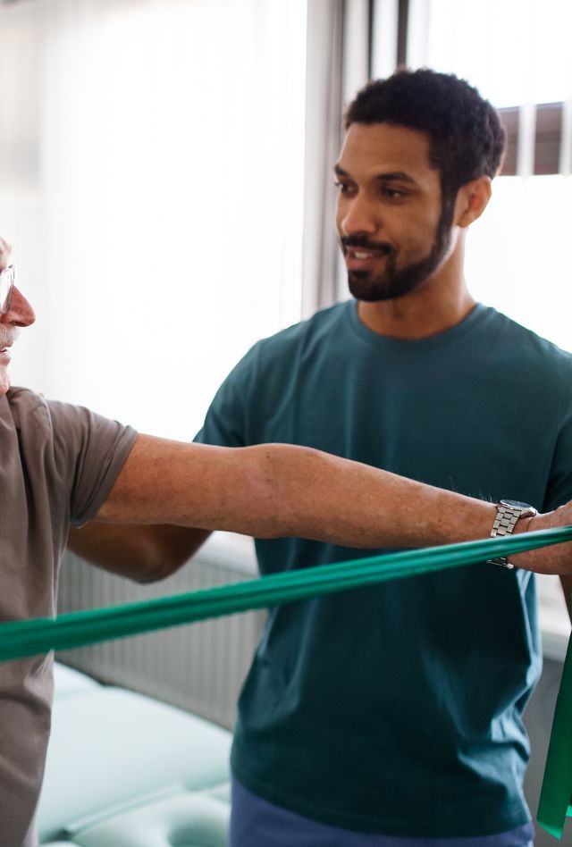 A young physiotherapist exercising with senior patient in a physic room