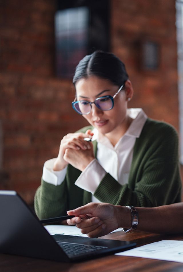 Two individuals seated at a table working together on a laptop, emphasizing teamwork and professionalism.
