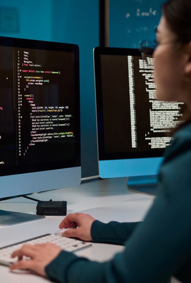 Woman in front of a computer with code lines on screen