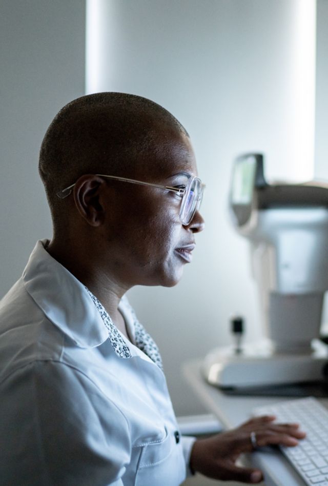 Black woman with short hair and classes looking at a computer screen