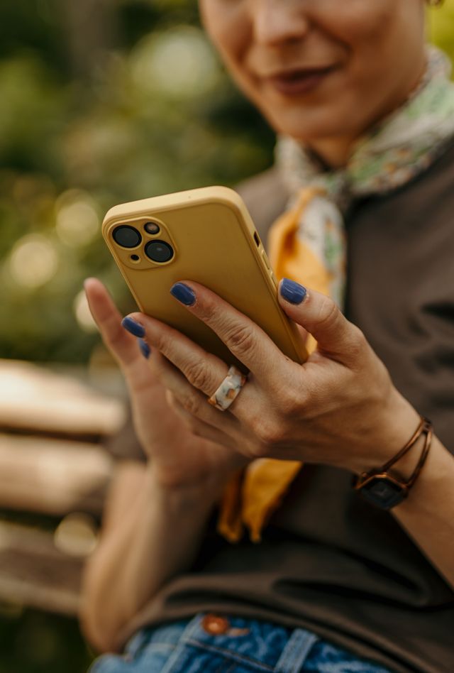 Woman using mobile phone while sitting on a bench in a park