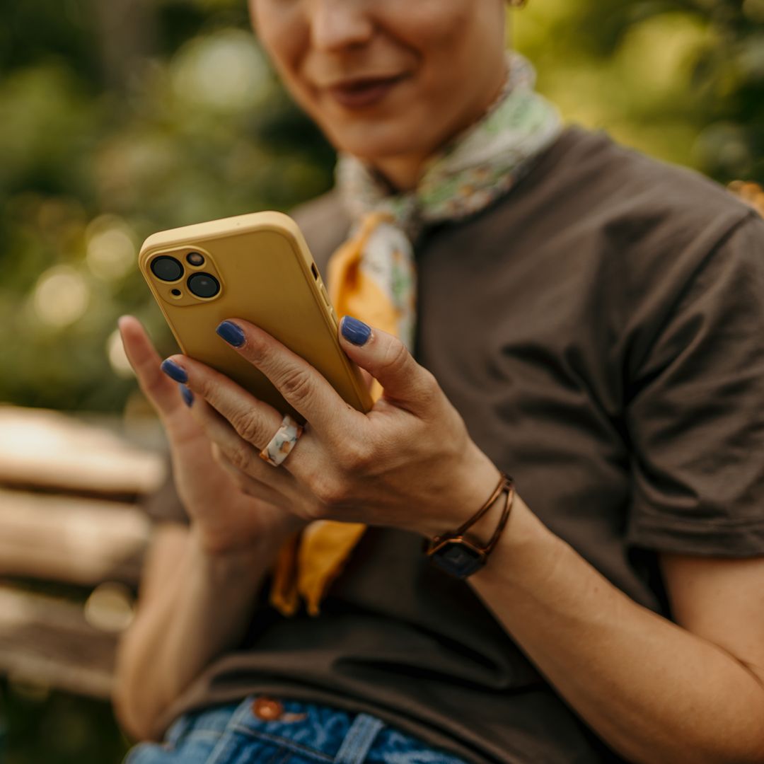 Woman using mobile phone while sitting on a bench in a park