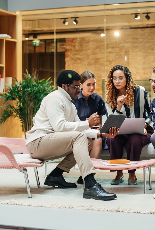 A group of people talks around a tablet in an office meeting room