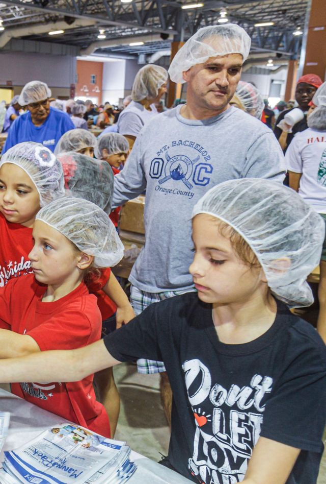 2GEMNX5 Miami Florida,Feed My Starving Children,volunteers volunteering working together packing meals,Hispanic girls children families wearing hairnets