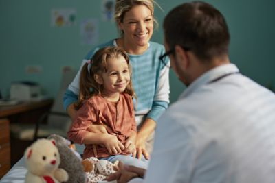 Smiling girl having a medical appointment at her doctor's office with a support of her single mother.
