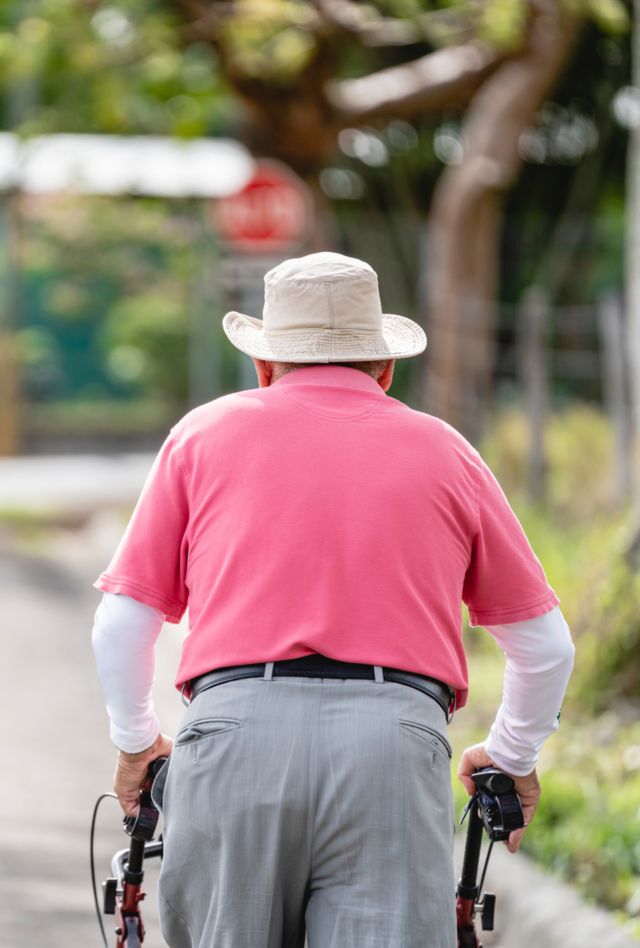 Unknown old man doing his morning walk with a walker on a beautiful sunny day