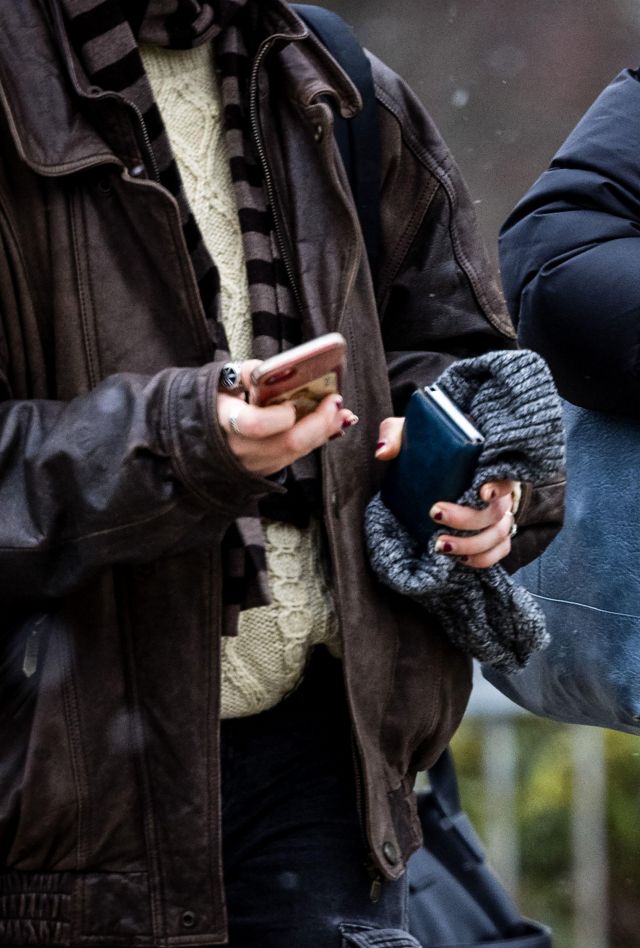 Close up of two people walking side by side as they text