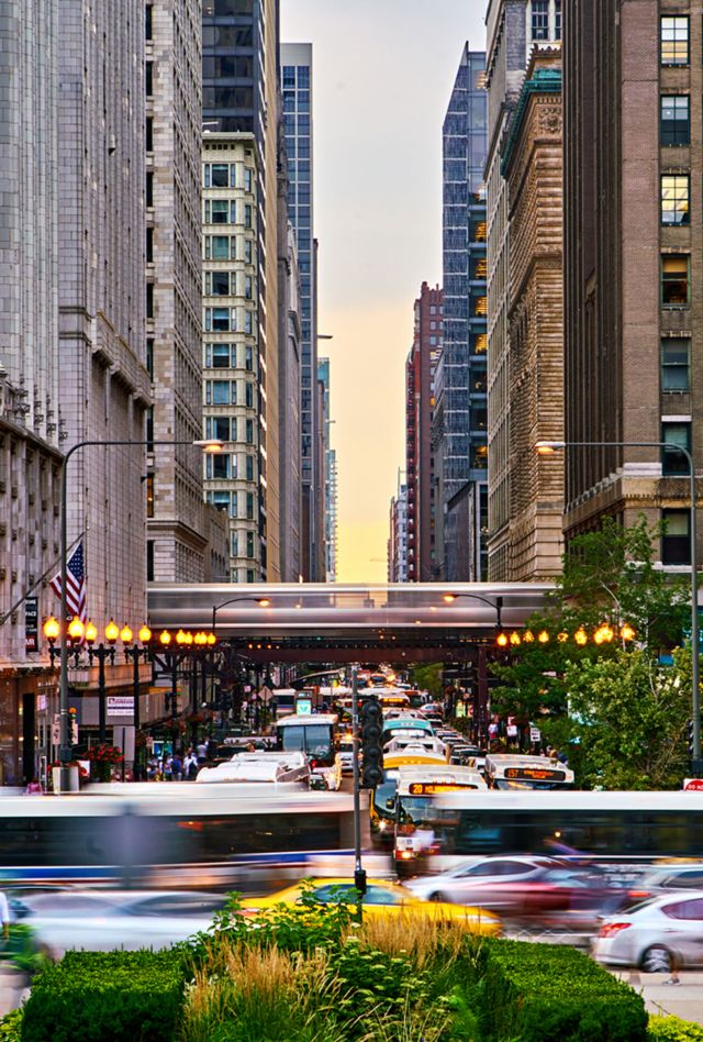 Chicago street with commuters in the foreground and buildings and the train in the  background