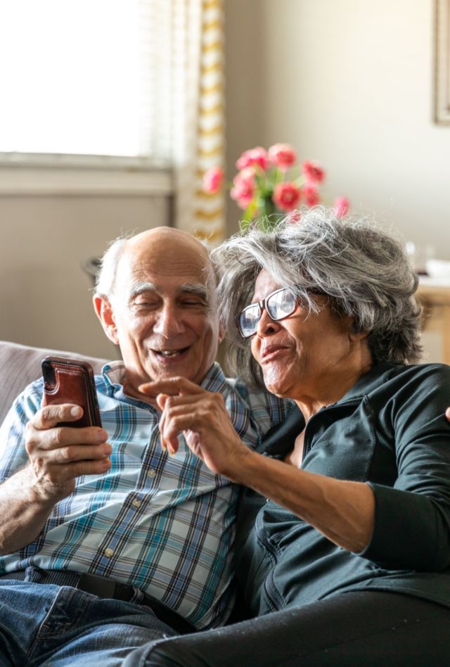 Couple looks at their phone and wife points.