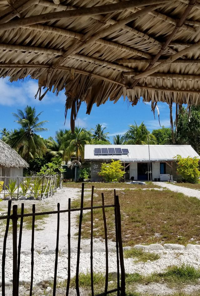 A school in Kiribati with three huts around a central grassy outdoor area