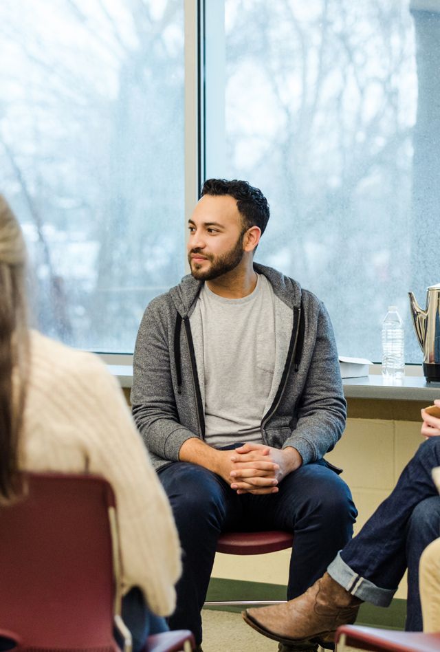 A multiracial, multigenerational group of military vets meet for group therapy on the Air Force base.