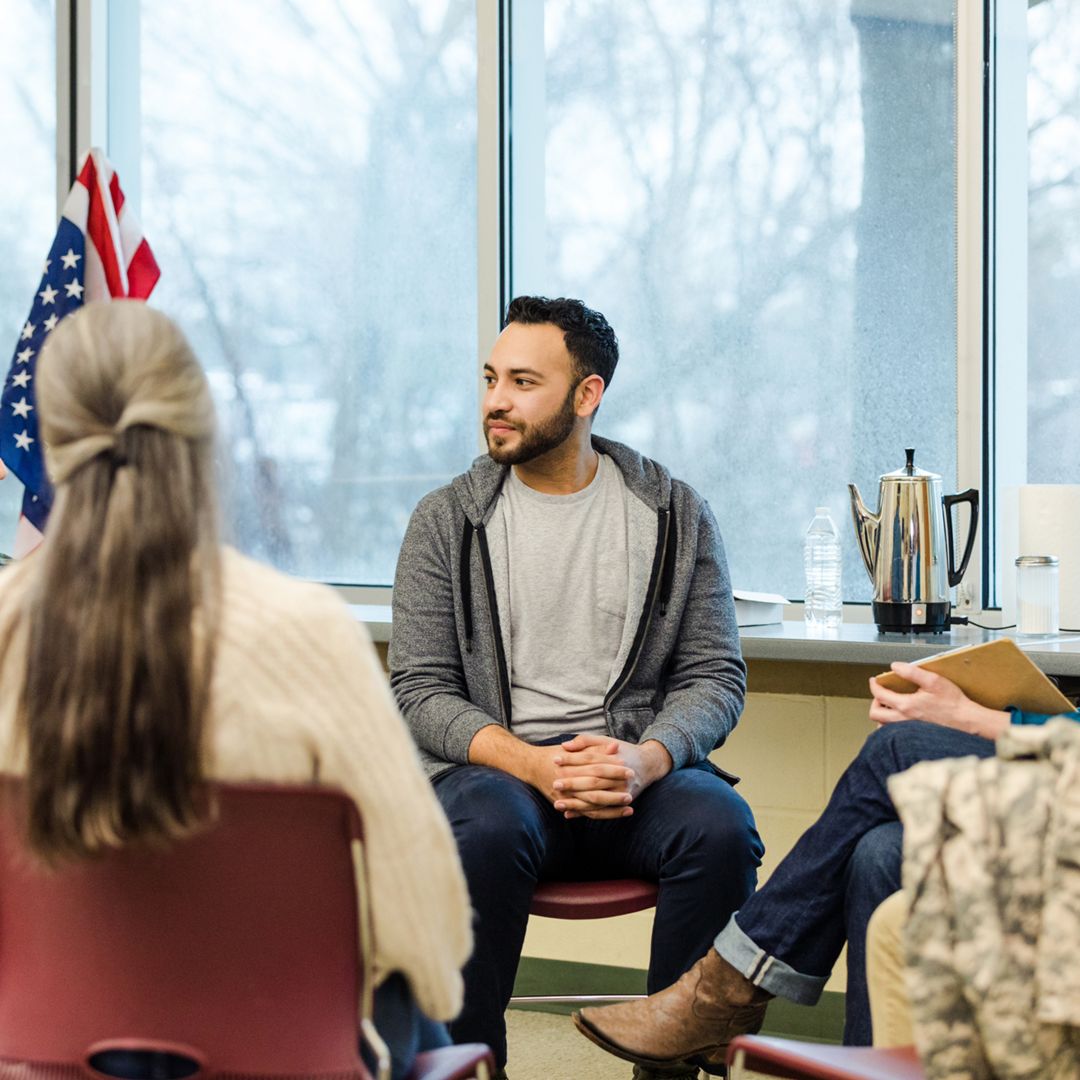 A multiracial, multigenerational group of military vets meet for group therapy on the Air Force base.