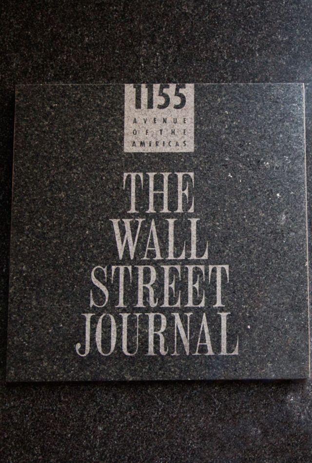 New York, New York, USA - August 03, 2013: The sign of "The Wall Street Journal" out of its building.  At right there are some people and buildings reflected by the marble.