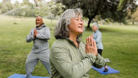 Three seniors doing yoga in the park