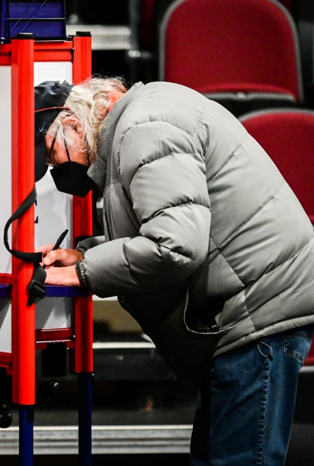 An older man casts his vote at a voting booth