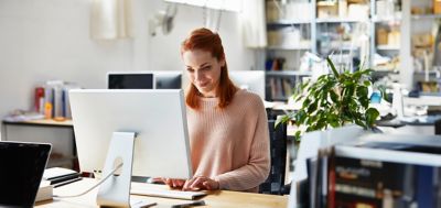 Smiling mid adult businesswoman using computer at office desk