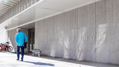 Man walks by a sign for The World Bank Group at their global headquarters in Washington, D.C.
