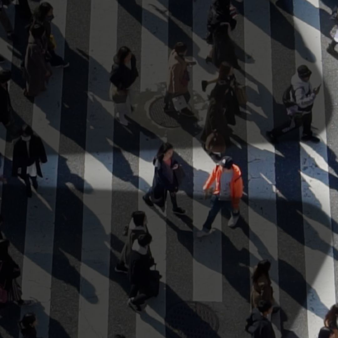 Overhead view of people walking across a crosswalk, with some people spotlighted in a spark shape