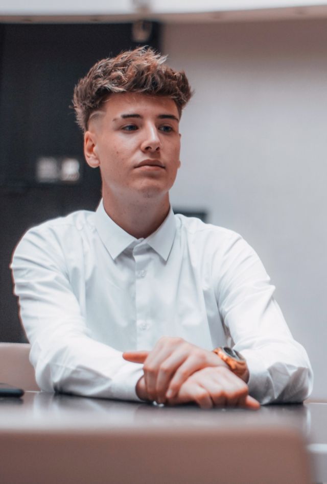 An adolescent boy sits across a table from a woman in a suit