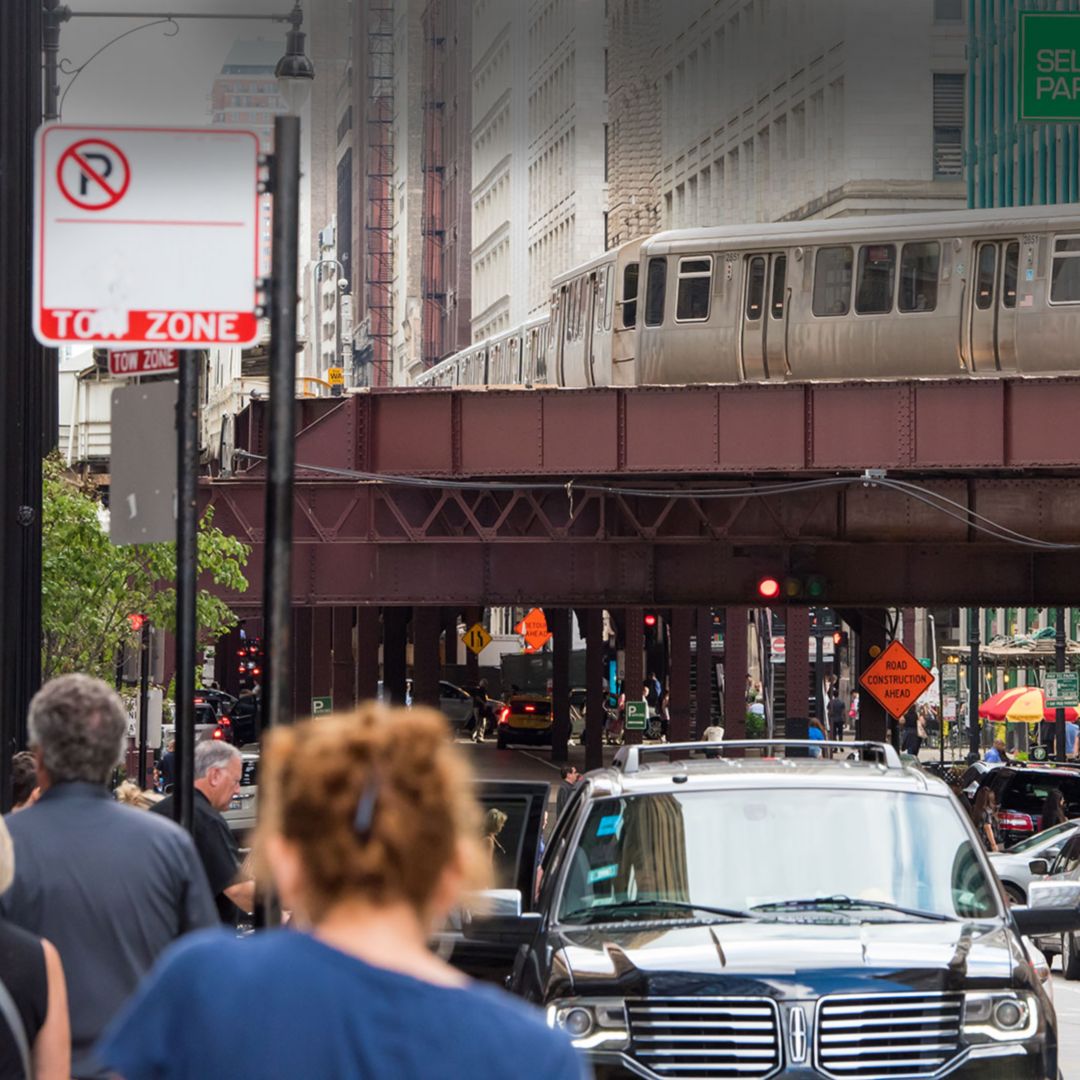 An elevated train running through Chicago's downtown with bustling streets below