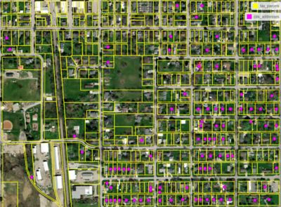 Aerial shot of residential neighborhood with plots outlined in yellow and purple dots on certain plots