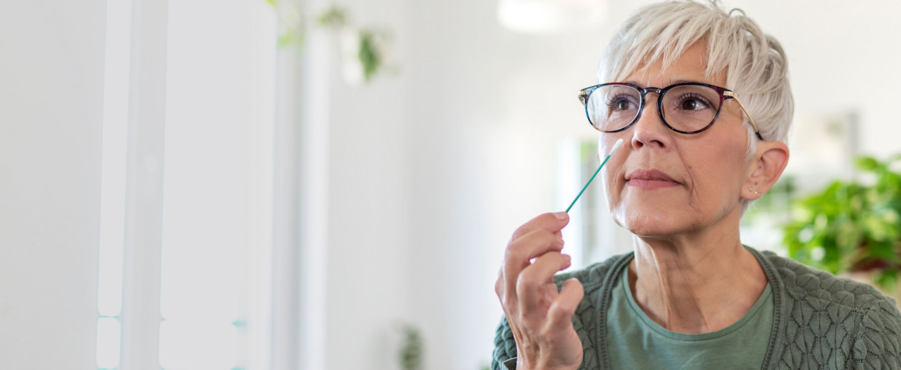 Woman swabbing her nose from an at home test kit