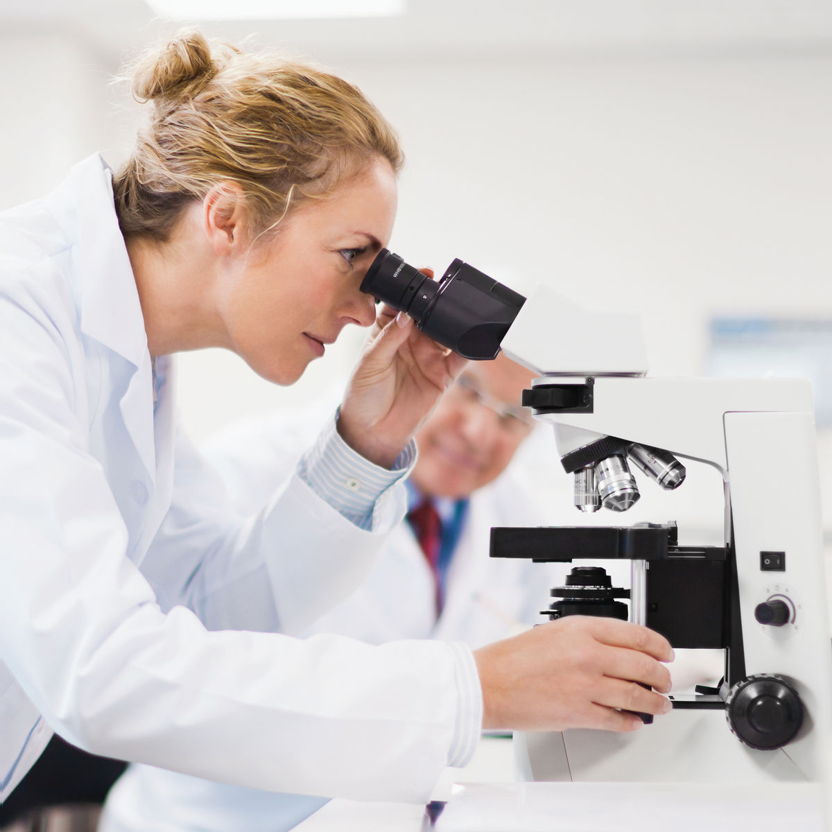 Laboratory professional using a microscope. /