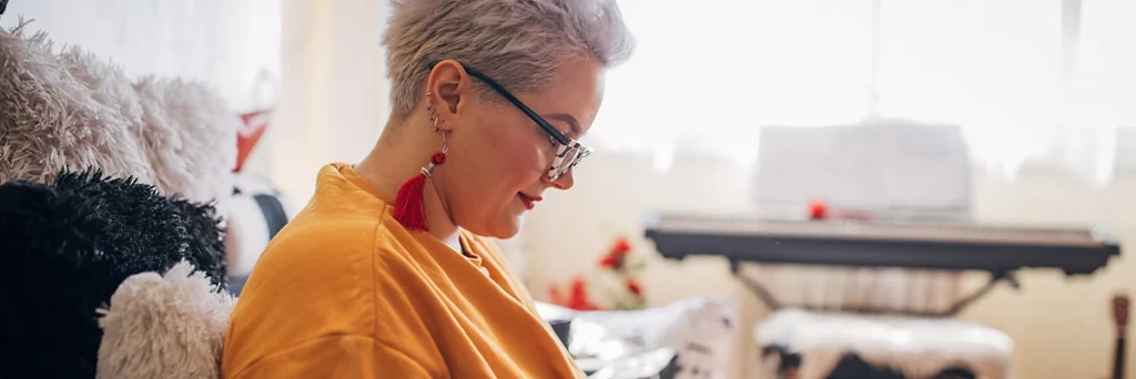 Woman sitting on sofa and using smart phone at home